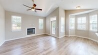 This two-story residence in D'Iberville, Mississippi offers a well-organized layout across two floors. The ground level houses an attached garage with a clean concrete floor, overhead lighting, and an automatic door opener, along with a hallway providing interior access to the main living areas above.

The upper floor is the heart of the home, featuring an open-concept kitchen and living room bathed in natural light from large windows with blinds. The kitchen is appointed with white shaker-style cabinetry, light quartz countertops, a stainless steel refrigerator, a subway tile backsplash, and light hardwood-style flooring that flows throughout the main living areas. A glass-paneled entry door with transom window and a charming bay window nook add architectural interest to the living space.

Both bedrooms are generously sized, featuring plush carpet, ceiling fans with light fixtures, and windows that bring in natural light. The spacious primary bedroom includes a walk-in closet outfitted with wire shelving on two walls. A dedicated laundry room with wire shelving, washer/dryer hookups, and hardwood-style flooring adds everyday convenience.

The two bathrooms feature white cabinetry with brushed nickel hardware, white countertops, and a tub/shower combo with built-in shelving, all finished with light hardwood-style flooring for a clean, cohesive aesthetic throughout.