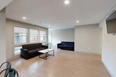 Located at 126 College Ave in Ithaca, NY, this spacious 7-bedroom, 3-bathroom unit offers a practical and functional layout designed to accommodate a large number of occupants comfortably. The single-floor layout connects a generously sized open living area to the kitchen, creating a cohesive communal space. The living room features light wood-style flooring, recessed lighting, and multiple windows that invite natural light, with seating for a large group and a central coffee table. Adjacent to the living area, the kitchen is well-equipped with stainless steel appliances — including a refrigerator, dishwasher, and range — along with ample cabinetry, a double sink, and light countertops. A dining table with seating connects the kitchen to the living space seamlessly. Each of the seven bedrooms is individually sized, with carpeted flooring, neutral-toned walls, and windows providing natural light and outdoor views of the surrounding neighborhood. The primary bedroom offers a comfortable footprint suitable for a full-sized bed and workspace. The three bathrooms are clean and modern, each featuring a vanity with storage, a mirror, and a shower/tub combination with wood-look flooring. Two hallways connect all spaces efficiently throughout the unit.