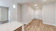 Located in Charlotte, NC, this thoughtfully designed one-bedroom, one-bathroom residence offers a cohesive and functional single-floor layout with modern finishes throughout. The kitchen serves as a standout feature, showcasing rich, medium-toned shaker-style cabinetry, light granite countertops, a classic white subway tile backsplash, and durable wood-look flooring. Stainless steel appliances — including a French door refrigerator, range, and dishwasher — complete this well-equipped culinary space. The open entryway and living area flow seamlessly from the kitchen, featuring the same warm wood-look flooring, recessed lighting, and neutral toned walls that create a bright, inviting atmosphere. The bedroom is a comfortable retreat, appointed with plush carpet flooring and a large triple-pane window fitted with blinds that frames views of the surrounding greenery, allowing generous natural light. A dedicated closet provides convenient storage. The bathroom is well-designed with an accessibility-friendly tub and shower combination, complete with grab bars and a removable shower bench. The vanity features granite countertops and dark wood cabinetry consistent with the kitchen, paired with wood-look flooring. This residence offers a clean, contemporary aesthetic with practical, thoughtful design details throughout.