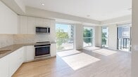 Located at 2475 Hurontario St in Mississauga, this 2-bedroom, 2-bathroom unit offers a thoughtfully designed layout across a single floor. The open-concept living and kitchen area is bathed in natural light through expansive floor-to-ceiling windows, with light hardwood flooring extending throughout and direct access to a private balcony overlooking a landscaped courtyard and playground area. The modern kitchen features white cabinetry, stainless steel appliances including a range and over-the-range microwave, and a herringbone tile backsplash. The generously sized primary bedroom includes mirrored sliding closet doors and large windows with outdoor views, while the second bedroom also benefits from floor-to-ceiling glazing and ample natural light. The two bathrooms are finished to a high standard — one features a sleek walk-in glass shower with a contemporary grey vanity and wood-look tile flooring, while the other showcases a soaker tub with elegant marble-effect tile surround. The balcony, equipped with glass panel railings, offers pleasant views of mature trees and the surrounding neighbourhood, providing a comfortable outdoor retreat.