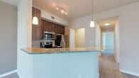 This well-appointed 2-bedroom, 2-bathroom residence is thoughtfully designed across a single floor, offering a comfortable and functional layout. The open-concept kitchen serves as the heart of the home, featuring rich dark-stained cabinetry, gleaming granite countertops, and a large peninsula that doubles as a breakfast bar. Stainless steel appliances, including a microwave, range, and refrigerator, complete the kitchen's modern aesthetic. Pendant lighting above the peninsula and track lighting overhead add both style and practicality to the space. Durable wood-look flooring flows throughout the main living areas, lending warmth and continuity to the design. The open floor plan connects the kitchen seamlessly to the living area, creating a bright and inviting atmosphere ideal for both everyday living and entertaining. A hallway leads to the two well-sized bedrooms, each offering privacy and comfort. With clean lines, neutral tones, and contemporary finishes throughout, this residence presents a polished and move-in-ready living environment suited for a variety of lifestyles.