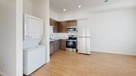 Located at 9917 Northeast 13th Avenue in Vancouver, WA, this thoughtfully designed 2-bedroom, 1-bathroom unit offers a bright, modern living environment across a single floor. Light wood-tone flooring runs throughout, creating a warm and cohesive aesthetic.

The open kitchen and living area serves as the heart of the unit. The kitchen is well-appointed with rich walnut-toned cabinetry, white countertops, a stainless steel refrigerator, range, microwave, and dishwasher. A stacked in-unit washer and dryer is conveniently positioned adjacent to the kitchen, adding everyday practicality.

Both bedrooms feature crisp white walls, wood-tone flooring, and individual closets. The primary bedroom is a cozy, functional space, while the second bedroom offers similar finishes with access to natural light through a window overlooking the surrounding landscape. Each bedroom includes a wall-mounted heater for year-round comfort.

The bathroom is clean and efficiently designed, featuring a full tub/shower combo with brushed nickel fixtures, wood-tone cabinetry, and coordinating flooring. A bright hallway connects all rooms, maintaining an open and airy feel throughout. This unit delivers a functional, modern layout ideal for everyday living.