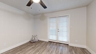 Located in Scottsdale, Arizona, this well-appointed one-bedroom, one-bathroom unit offers a thoughtfully designed single-level layout that maximizes every square foot of its compact footprint. The interior is unified by light-toned luxury vinyl plank flooring that flows throughout every room, creating a clean and cohesive aesthetic.

The open kitchen and living room combination serves as the heart of the unit. The kitchen features crisp white cabinetry, white countertops, and a full suite of stainless steel appliances including a refrigerator, dishwasher, over-the-range microwave, and range. A skylight-style ceiling fixture keeps the kitchen bright and functional. The adjoining living area benefits from a set of French doors fitted with white horizontal blinds, allowing natural light to filter in while offering access to the outdoors. A ceiling fan overhead adds comfort to the space.

The bedroom is a well-proportioned retreat with its own ceiling fan, a window with blinds for natural light, and a dedicated closet. A hallway connects the main living areas to the bedroom and bathroom. The bathroom features a wide vanity with a white countertop and a large mirror, alongside a full tub and shower combination. Neutral tones and clean finishes carry throughout, giving the entire unit a fresh, move-in-ready feel.
