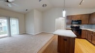 Located at 420 Salt Meadow Cir in Bradenton, Florida, this single-floor, one-bedroom, two-bathroom home offers a well-designed layout across a comfortable footprint. The open-concept living and kitchen area is a standout feature, with vaulted ceilings enhanced by a ceiling fan that amplify the sense of space and airiness. Hardwood flooring flows through the kitchen and entry areas, transitioning to plush carpet in the living room and bedroom.

The kitchen is well-appointed with rich dark-wood cabinetry, a mosaic tile backsplash, granite countertops, black appliances including a range, dishwasher, refrigerator, and microwave, plus a central island with additional granite surface space and a stylish pendant light overhead. A hallway with an arched entryway connects the main living area to the private quarters.

The primary bedroom is generously sized, carpeted, and features a ceiling fan and access to natural light. Three closets provide ample storage throughout the home. Both bathrooms are finished with granite-topped vanities, rich wood cabinetry, and tile flooring. One bathroom includes a full soaking tub with tiled surround. A utility room and dedicated hallway round out the functional layout. Sliding glass doors in the living area open to a private balcony, adding an outdoor connection to this Florida home.