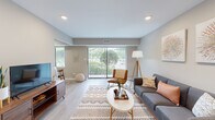 Located at 1501 E Central Rd in Arlington Heights, IL, this single-floor residence offers a thoughtfully designed 1-bedroom, 2-bathroom layout that maximizes both comfort and functionality. The open-concept living room features light hardwood-style flooring, recessed lighting, and a large sliding glass door that floods the space with natural light while providing a view of lush greenery outside. The living area flows seamlessly into the dining space, which includes a dedicated nook with a window, and into the kitchen. The kitchen is well-equipped with rich dark-wood cabinetry, quartz countertops, a gray subway tile backsplash, stainless steel appliances including a refrigerator, range, microwave, and dishwasher, and a deep single-basin sink. The spacious primary bedroom features plush carpeting, a bold accent wall in deep teal, natural window light, and generous closet space with bifold doors. Both bathrooms are finished with warm earth-toned tile, including a full bath with a tub-shower combination and dark wood vanity cabinetry. A hallway connects the private areas of the home, completing a functional and cohesive floor plan throughout.
