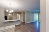 Located at 6263 Rivoli Dr in Chattanooga, TN, this single-story residence offers a thoughtfully designed open-concept layout that seamlessly connects the kitchen, dining, and living areas. The kitchen is a standout feature, showcasing white shaker cabinetry, granite countertops, stainless steel appliances including a gas range, built-in microwave, and refrigerator, along with track lighting overhead. A kitchen island with a sink and breakfast bar provides additional prep space and casual seating. The dining area is highlighted by crown molding and an elegant chandelier, while the living room is finished with hardwood-style flooring and a ceiling fan. The bedroom is a comfortable retreat, carpeted with a ceiling fan and natural light from a window with blinds. The walk-in closet offers wire shelving for organized storage. The bathroom features hardwood-style flooring, a tub-shower combination with tile surround, and accessibility grab bars. A dedicated laundry area accommodates a stacked washer and dryer unit. Neutral warm-gray tones carry throughout, creating a cohesive and modern ambiance across every room.