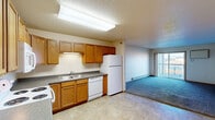 This single-floor unit is designed with a practical, straightforward layout that accommodates comfortable everyday living. The kitchen is well-equipped with warm oak cabinetry, dark granite-style countertops, a double sink, and a full suite of white appliances including a refrigerator, dishwasher, range, and microwave. Tile flooring runs throughout the kitchen, transitioning to plush carpet in the adjacent living area, which receives natural light from a sliding glass door leading to a private balcony.

The bedrooms are carpeted and offer neutral wall tones, with one bedroom featuring its own sliding door access to an outdoor area. A spacious walk-in closet with wire shelving provides generous storage and connects directly to one of the two full bathrooms. Both bathrooms are finished with tile flooring, oak vanities, dark countertops, and tub-shower combinations, with baseboard heating for comfort. A dedicated in-unit laundry room includes a full-size washer and dryer and additional shelving overhead. Baseboard heating is present throughout, and textured ceilings are consistent across the unit.
