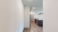 This thoughtfully designed 2-bedroom, 2-bathroom single-floor residence offers a functional and modern living experience. The open-concept kitchen is a standout, featuring dark espresso cabinetry, granite countertops, a large center island, and a full suite of stainless steel appliances including a side-by-side refrigerator, electric range, built-in microwave, and dishwasher. Striking pendant lights hang above the island, complementing the wood-look luxury vinyl flooring that flows seamlessly into the living area. The living space is bright and airy, benefiting from multiple windows and a glass-panel door that invites natural light, with a ceiling fan adding comfort overhead. Both bedrooms feature plush carpeting, and the primary bedroom includes direct access to an en suite bathroom equipped with a walk-in shower with tile surround, as well as a dedicated walk-in closet with built-in shelving. The second bathroom offers a tiled soaking tub and shower combination with a granite-topped vanity. A dedicated in-unit laundry room accommodates a full-size washer and dryer with overhead shelving for added storage. Two closets throughout the unit enhance organizational options, completing this well-rounded and move-in-ready residence.