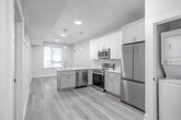 Located at 342 W Girard Ave in Philadelphia's vibrant Northern Liberties neighborhood, this thoughtfully designed unit offers three bedrooms and one bathroom across a single floor. Light-toned luxury vinyl plank flooring runs throughout, creating a cohesive and modern aesthetic from room to room.

The kitchen is a standout feature, boasting white shaker cabinetry extending to the ceiling, a marble-look peninsula countertop with a built-in sink, and a full suite of stainless steel appliances including a French door refrigerator, range, over-the-range microwave, and dishwasher. Elegant pendant lighting completes the contemporary feel.

A central hallway connects the living areas to the bedrooms, which are bright and clean with neutral walls and light wood flooring. Bedrooms are equipped with organized closets featuring built-in shelving and hanging rods, maximizing storage efficiency. One bedroom benefits from a large window with views of the surrounding neighborhood, allowing ample natural light.

The bathroom is finished in a crisp, all-white palette with marble-style tile flooring, a floating vanity with a sleek rectangular mirror, and a tub-shower combination. Recessed lighting throughout the unit adds a polished finishing touch to this well-appointed Philadelphia residence.