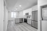 Located at 342 W Girard Ave in Philadelphia's vibrant Northern Liberties neighborhood, this thoughtfully designed unit offers three bedrooms and one bathroom across a single floor. Light-toned luxury vinyl plank flooring runs throughout, creating a cohesive and modern aesthetic from room to room.

The kitchen is a standout feature, boasting white shaker cabinetry extending to the ceiling, a marble-look peninsula countertop with a built-in sink, and a full suite of stainless steel appliances including a French door refrigerator, range, over-the-range microwave, and dishwasher. Elegant pendant lighting completes the contemporary feel.

A central hallway connects the living areas to the bedrooms, which are bright and clean with neutral walls and light wood flooring. Bedrooms are equipped with organized closets featuring built-in shelving and hanging rods, maximizing storage efficiency. One bedroom benefits from a large window with views of the surrounding neighborhood, allowing ample natural light.

The bathroom is finished in a crisp, all-white palette with marble-style tile flooring, a floating vanity with a sleek rectangular mirror, and a tub-shower combination. Recessed lighting throughout the unit adds a polished finishing touch to this well-appointed Philadelphia residence.
