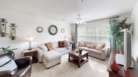 Located at 2309 Providence Pointe Ln in Winston-Salem, NC, this single-floor residence offers a thoughtfully designed layout that balances comfort and functionality throughout. The spacious living room is bathed in natural light from large windows dressed with elegant teal drapes, and features plush carpeting, a ceiling fan, and ample room for relaxed seating arrangements. Adjacent to the living area, a dedicated dining space provides an intimate setting for meals, accented by warm, neutral-toned walls that carry consistently throughout the home. The kitchen features light wood cabinetry, white countertops, and tile flooring, with a hallway connecting it seamlessly to the rest of the home, including a full bathroom with a tub-shower combination and vanity. The primary bedroom is generously sized with soft carpeting, a ceiling fan, natural window light, and access to a walk-in closet. A second bedroom mirrors this comfort with its own ceiling fan and ample space. Both bedrooms are designed with restful, neutral palettes. The home's cohesive design — marked by consistent warm tones, carpet and tile flooring, and ceiling fans throughout — creates a welcoming and practical living environment well-suited for everyday comfort.