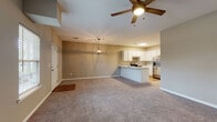 This single-story residence offers a functional, open-concept layout that seamlessly connects the living area to the kitchen. The living space features warm neutral-toned walls, plush carpet flooring, and ceiling fans with light fixtures that provide both comfort and illumination. A decorative pendant light hangs above the kitchen transition area, adding a stylish accent.

The kitchen is well-equipped with white shaker-style cabinetry, light granite countertops, and a full suite of stainless steel appliances, including an electric range, built-in microwave, dishwasher, and a French door refrigerator. Durable wood-look flooring runs throughout the kitchen, complementing the clean, bright aesthetic. A peninsula with a sink and breakfast bar connects the kitchen to the living space.

The bedrooms are carpeted and finished with the same neutral palette, each featuring ceiling fans and windows with blinds that allow natural light. The bathrooms are outfitted with white cabinetry, granite-topped vanities, and wood-look flooring. One bathroom includes a tub-shower combination, while the other features additional storage and a dedicated towel bar area, rounding out this cohesive and practical living space.
