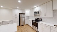 This single-floor space showcases a thoughtfully updated interior with a clean, modern aesthetic throughout. The open-concept living and kitchen area is a standout feature, with light hardwood-style flooring, recessed lighting, and a seamless flow between the two spaces. A peninsula counter creates a natural division while maintaining the open feel of the combined area.

The kitchen is well-appointed with white shaker-style cabinetry extending from floor to ceiling, providing generous storage. White subway tile backsplash lines the walls, complementing the light quartz countertops. Stainless steel appliances include a refrigerator, electric range, over-the-range microwave, and dishwasher, delivering a cohesive and functional cooking environment.

The bedrooms feature warm hardwood-style flooring and ceiling fans, with windows fitted with blinds allowing for natural light control. The rooms offer a neutral palette suited to a variety of furnishing styles.

Two bathrooms serve the unit. One includes a glass-enclosed corner shower with white subway tile surround and brushed nickel fixtures, paired with a white shaker vanity and a black-framed mirror. The second bathroom features a full soaking tub with a subway-tiled surround and a sliding shower rod, providing practical versatility.