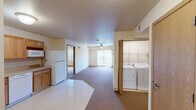 Located at 1050 Flammang Dr in Waterloo, Iowa, this single-floor, 2-bedroom, 2-bathroom residence offers a practical and comfortable layout designed with accessibility in mind. The open-concept kitchen and living area forms the heart of the home, with the kitchen featuring warm oak cabinetry, generous counter space, and white appliances including a range, dishwasher, microwave, and refrigerator. Light tile flooring transitions into plush carpeting throughout the living and bedroom areas. The spacious living room is brightened by a large sliding glass door that brings in natural light and provides outdoor access, complemented by a ceiling fan overhead. A dedicated in-unit laundry area with a washer and dryer adds everyday convenience. Both bedrooms are well-sized, carpeted, and equipped with ceiling fans and natural light from windows with outdoor views. Each bedroom benefits from multiple closets for ample storage. The two bathrooms are thoughtfully designed with accessibility features, including grab bars; one offers a roll-in shower, while the other includes a shower-tub combination. Both bathrooms feature oak vanities with mirrored medicine cabinets. The overall ambiance is clean, neutral, and functional throughout.