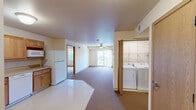 Located at 1050 Flammang Dr in Waterloo, Iowa, this single-floor, 2-bedroom, 2-bathroom residence offers a practical and comfortable layout designed with accessibility in mind. The open-concept kitchen and living area forms the heart of the home, with the kitchen featuring warm oak cabinetry, generous counter space, and white appliances including a range, dishwasher, microwave, and refrigerator. Light tile flooring transitions into plush carpeting throughout the living and bedroom areas. The spacious living room is brightened by a large sliding glass door that brings in natural light and provides outdoor access, complemented by a ceiling fan overhead. A dedicated in-unit laundry area with a washer and dryer adds everyday convenience. Both bedrooms are well-sized, carpeted, and equipped with ceiling fans and natural light from windows with outdoor views. Each bedroom benefits from multiple closets for ample storage. The two bathrooms are thoughtfully designed with accessibility features, including grab bars; one offers a roll-in shower, while the other includes a shower-tub combination. Both bathrooms feature oak vanities with mirrored medicine cabinets. The overall ambiance is clean, neutral, and functional throughout.