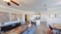 Located in Austin, TX, this single-story 2-bedroom, 2-bathroom home offers a thoughtfully designed open-concept layout that seamlessly connects the living room, dining area, and kitchen. The living room is finished with crown molding, wood-look flooring, and a ceiling fan, creating a bright and welcoming atmosphere enhanced by large windows that invite abundant natural light. An elegant arched entryway leads between spaces, adding a classic architectural touch. The kitchen features white cabinetry, stainless steel appliances, and a peninsula with bar seating, flowing directly into a dedicated dining nook with a large window overlooking the outdoors. The spacious primary bedroom is carpeted and bathed in soft light, with a ceiling fan overhead and access to an en-suite bathroom appointed with granite countertops and white cabinetry. A generous walk-in closet with wire shelving provides excellent storage. The second bedroom is equally comfortable with plush carpet and ample space. A dedicated laundry room houses a full-size washer and dryer. Throughout the home, neutral tones, crown molding, and consistent flooring contribute to a cohesive and polished aesthetic ideal for comfortable everyday living.
