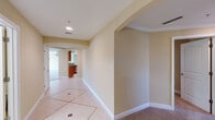 This single-floor residence showcases a cohesive design throughout, characterized by warm beige and cream tones, clean white baseboards and crown molding, and a thoughtful mix of tile and carpet flooring. Arched doorways and passageways lend an elegant architectural touch, guiding movement between rooms with visual continuity.

The hallways are finished with large-format tile flooring accented by inlaid border detailing, creating a polished entryway experience. Recessed lighting illuminates the corridors, which lead seamlessly to the main living areas, finished in plush neutral carpet and framed by tray ceiling details that add dimension to the space.

The kitchen is well-equipped with rich warm-toned wood cabinetry, granite countertops with natural veining, and stainless steel appliances including a side-by-side refrigerator with an in-door dispenser. Ample upper and lower cabinet storage provides generous functionality.

The bathrooms feature warm wood vanity cabinetry paired with light countertops and large wall mirrors. Tile flooring continues through these spaces, maintaining a consistent and clean aesthetic. A utility area houses a water heater and laundry hookups, adding practical infrastructure to the layout.

Overall, the space presents a neutral, move-in-ready palette with classic architectural details throughout.