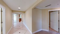 This single-floor residence showcases a cohesive design throughout, characterized by warm beige and cream tones, clean white baseboards and crown molding, and a thoughtful mix of tile and carpet flooring. Arched doorways and passageways lend an elegant architectural touch, guiding movement between rooms with visual continuity.

The hallways are finished with large-format tile flooring accented by inlaid border detailing, creating a polished entryway experience. Recessed lighting illuminates the corridors, which lead seamlessly to the main living areas, finished in plush neutral carpet and framed by tray ceiling details that add dimension to the space.

The kitchen is well-equipped with rich warm-toned wood cabinetry, granite countertops with natural veining, and stainless steel appliances including a side-by-side refrigerator with an in-door dispenser. Ample upper and lower cabinet storage provides generous functionality.

The bathrooms feature warm wood vanity cabinetry paired with light countertops and large wall mirrors. Tile flooring continues through these spaces, maintaining a consistent and clean aesthetic. A utility area houses a water heater and laundry hookups, adding practical infrastructure to the layout.

Overall, the space presents a neutral, move-in-ready palette with classic architectural details throughout.
