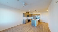 This two-floor residence showcases a clean, modern design with a neutral palette and quality finishes throughout. The main level features light hardwood-style flooring that extends through the open living area and into the kitchen. The kitchen is well-appointed with warm wood-tone cabinetry extending to the ceiling, white quartz countertops, a tile backsplash, and a full suite of stainless steel appliances including a range, microwave, and French door refrigerator with an ice and water dispenser. A central island with a built-in sink provides additional workspace and adds to the kitchen's functional layout. A ceiling fan overhead enhances comfort in the main living space, which also features recessed lighting. A staircase with wood-tread steps connects the two levels. The upper floor includes carpeted bedrooms that benefit from natural light through standard windows, with mountain views visible from at least one room. A walk-in closet with dual hanging rods and shelving provides generous storage. The primary bathroom offers hardwood-style flooring, a double-sink vanity with modern fixtures, a glass-enclosed shower, and access to the walk-in closet. A secondary bathroom includes a tub-shower combination, a single vanity, and a high window for natural light. Throughout, the interiors maintain a bright, cohesive aesthetic with white walls and consistent finishes.