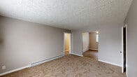 Located at 99 Patterson Village Dr in Dayton, Ohio, this single-floor unit offers three bedrooms, one bathroom, a kitchen, and a hallway within a efficiently arranged layout. Neutral gray walls and textured ceilings are consistent throughout, creating a cohesive and understated aesthetic.

The living area features warm tan carpeting and baseboard heating, with doorways leading to the bedrooms and providing an open flow through the unit. Two of the bedrooms feature wood-look laminate flooring, ceiling fans, and windows that bring in natural light and views of surrounding greenery. The primary bedroom is generously sized and includes carpet flooring, panel-style closet doors, and baseboard heating. A third bedroom is carpeted and also equipped with baseboard heating and a window-mounted air conditioning unit.

The kitchen is functional and bright, showcasing white cabinetry, a light-toned countertop with an integrated sink, wood-look flooring, and a ceiling fan overhead. A white refrigerator and gas range complete the space.

The bathroom is a standout with its retro character, featuring pink ceramic wall tiles accented by dark border trim, a tub-shower combination, and a window that allows natural light to filter in. Baseboard heating is present throughout, ensuring comfort across all seasons.