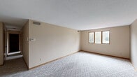 Located at 1616 S Main St in North Canton, Ohio, this single-floor residence offers two bedrooms, two bathrooms, and a thoughtfully organized layout. The spacious living room features neutral-toned walls, plush patterned carpeting, and a wide window that invites natural light and outdoor views of surrounding greenery. A thermostat on the wall and ceiling vents reflect a well-maintained climate control system throughout.

The primary bedroom is generously sized, appointed with the same soft carpeting and warm wood-trimmed closet doors that provide ample storage. A secondary bedroom also features carpeting, a window with natural light, and a ceiling light fixture. Notably, the residence includes six closets in total, ensuring exceptional storage capacity throughout.

The galley-style kitchen is lined with rich wood cabinetry, offering substantial counter and storage space, and is equipped with a range and refrigerator. The flooring transitions to a resilient surface suited for the kitchen environment.

The two bathrooms are well-appointed: one features a white vanity with a large mirror and neutral gray walls, while the second offers a full tub, tiled walls, a double-sink vanity, and mosaic tile flooring. A dedicated dining room, entrance, and hallway round out the functional and connected floor plan of this North Canton home.