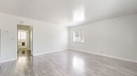 Located at 390 N Madison Ave in Pasadena, California, this efficiently designed single-floor unit offers a clean, modern aesthetic throughout its well-organized layout, comprising a living room, hallway, and bathroom.

The living room serves as the central space of the unit, finished with light grey wood-style laminate flooring that runs throughout and crisp white walls that maximize the sense of brightness. Natural light filters in through a window fitted with horizontal blinds, while a front entry door with a arched transom window adds architectural character. A wall-mounted air conditioning unit provides climate control, and clean white baseboards frame the room neatly.

A hallway connects the living area to the bathroom and features built-in white cabinetry with multiple drawers and tall storage panels, offering generous organizational capacity within a compact footprint.

The bathroom continues the clean, contemporary palette with white cabinetry, a granite-topped vanity in warm gold tones, an undermount sink with brushed nickel fixtures, and a mirrored medicine cabinet above. The flooring transitions to a darker wood-style finish, adding visual contrast.

Overall, the unit presents a bright, move-in-ready atmosphere with cohesive finishes, practical built-in storage, and a straightforward layout well-suited for efficient single-occupant living in the heart of Pasadena.