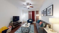 This single-floor residence in Killeen, Texas offers a well-designed layout that balances comfort and functionality throughout. The living room serves as the heart of the home, featuring rich hardwood-style flooring, crown molding, and a ceiling fan overhead. Large windows dressed with bold patterned curtains allow natural light to fill the space, creating a bright and inviting atmosphere. A dedicated dining area adjacent to the living space provides an intimate setting for meals, framed by crisp white walls. The kitchen is efficiently designed with dark cabinetry, black appliances including a refrigerator, stove, and built-in microwave, along with a breakfast bar that connects seamlessly to the main living areas. The bedrooms are carpeted and well-proportioned, each featuring windows with blinds that allow for adjustable natural light. Two full bathrooms are finished with hardwood-style flooring, vanities with dark cabinetry, and shower-tub combinations, offering practical and clean spaces. Throughout the home, the consistent use of hardwood-style flooring in the main areas and neutral wall tones creates a cohesive and polished aesthetic. The single-level floorplan ensures easy accessibility and efficient flow between all areas of the home.