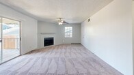 Located at 301 N Roadrunner Pkwy in Las Cruces, NM, this 2-bedroom, 1-bathroom unit offers a well-organized single-floor layout. The open living room is a standout, featuring plush carpeting, a ceiling fan with light fixture, a classic wood-mantel fireplace, and a sliding glass door that opens to a private balcony. Natural light flows in through multiple windows, creating a bright and comfortable atmosphere throughout.

The galley-style kitchen is efficiently designed with white cabinetry, stainless steel appliances including a refrigerator and range, a double-basin sink, light wood-style flooring, and a tile backsplash accent. A hallway connects the main living areas to the bedrooms and bathroom.

Both bedrooms feature soft carpeting and ceiling fans. The primary bedroom includes mirrored sliding closet doors that enhance the sense of space. The second bedroom also benefits from a natural window view with greenery outside.

The bathroom is cleanly appointed with a tiled tub-shower combination, a single vanity with a large mirror, and light wood-style flooring consistent with the rest of the unit. Textured ceilings are present throughout, contributing to the unit's cohesive, understated aesthetic.