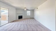 Located at 301 N Roadrunner Pkwy in Las Cruces, NM, this 2-bedroom, 1-bathroom unit offers a well-organized single-floor layout. The open living room is a standout, featuring plush carpeting, a ceiling fan with light fixture, a classic wood-mantel fireplace, and a sliding glass door that opens to a private balcony. Natural light flows in through multiple windows, creating a bright and comfortable atmosphere throughout.

The galley-style kitchen is efficiently designed with white cabinetry, stainless steel appliances including a refrigerator and range, a double-basin sink, light wood-style flooring, and a tile backsplash accent. A hallway connects the main living areas to the bedrooms and bathroom.

Both bedrooms feature soft carpeting and ceiling fans. The primary bedroom includes mirrored sliding closet doors that enhance the sense of space. The second bedroom also benefits from a natural window view with greenery outside.

The bathroom is cleanly appointed with a tiled tub-shower combination, a single vanity with a large mirror, and light wood-style flooring consistent with the rest of the unit. Textured ceilings are present throughout, contributing to the unit's cohesive, understated aesthetic.