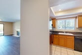 Located at 21495 LeMay Dr in Riverside, CA, this single-story home offers a practical and comfortable layout across two bedrooms and two bathrooms. The open-concept living and dining area is spacious and bright, featuring warm wood-style flooring and a sliding glass door that invites natural light while providing access to the outdoor patio. The kitchen is well-equipped with honey-toned wood cabinetry, dark granite countertops, a breakfast bar peninsula, white tile flooring, and black appliances including a refrigerator, dishwasher, and range — all beneath a recessed tray ceiling. A utility room adds functional storage. The bedrooms are comfortably sized, with the generously proportioned primary bedroom featuring plush carpeting and a window with outdoor views. Both bathrooms include tile flooring, wood vanities with granite countertops, and one features a full shower-tub combination with sliding glass doors. Ample closet space is found throughout, with eight closets distributed across the home. The attached garage provides secure parking and additional storage. Neutral warm tones throughout the interior create a cohesive and welcoming ambiance, making this single-floor home a practical and inviting residence.