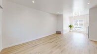This 490 square foot, one-bedroom apartment in Los Angeles offers a well-designed living space with modern amenities. The interior showcases a cohesive design with light wood flooring throughout, creating a warm and inviting atmosphere. The living room is bright and airy, featuring recessed lighting and a window that allows natural light to flood the space. The bedroom, measuring 100 square feet, includes a sliding closet door for efficient storage.

The bathroom boasts a luxurious touch with marble-like tiled walls surrounding the bathtub, complemented by brass fixtures. The kitchen is a highlight, featuring crisp white cabinetry, a gas stove, and a flexible faucet, all designed for both functionality and style. The apartment's layout maximizes the available space, with a hallway connecting the various rooms.

Energy-efficient elements are evident, including a wall-mounted air conditioning unit and windows with blinds for temperature control. The overall design aesthetic is clean and minimalist, with smooth white walls that provide a blank canvas for personalization. This apartment is an excellent example of modern, compact living that doesn't compromise on style or comfort.