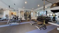 Located at 1001 Archdale Dr in Franklin, Tennessee, this single-floor fitness and recreation facility is thoughtfully designed to support a wide range of health and wellness activities. The main gym area is generously proportioned and divided into distinct functional zones. The cardio section houses professional-grade Life Fitness ellipticals, rowing machines, and a stair climber, all positioned near large windows that invite abundant natural light. A dedicated strength training area features a multi-station cable machine, adjustable benches, a full dumbbell rack with TRX suspension trainers, and a wall-mounted flat-screen television. Large framed mirrors line the walls throughout, amplifying the sense of space. A separate studio area with warm hardwood flooring, a ballet barre, wall mirror, and a rack of stability balls provides an ideal space for yoga, stretching, or group classes. This studio opens directly to a lush outdoor green space via floor-to-ceiling glass sliding doors. A built-in hydration station with a stainless steel water fountain and storage hooks adds practical convenience. Adjacent to the gym is a vibrant children's playroom with bold navy blue walls, soft textured carpeting, a hopscotch play rug, a white activity table, modular bookshelves, and ample toy storage, creating a lively and functional space for younger occupants.