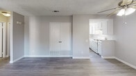 Located at 42200 Moraga Rd in Temecula, California, this single-floor unit offers a clean, functional layout with a consistent design palette throughout. Wood-style plank flooring runs through the main living areas and bedrooms, complemented by neutral gray walls and white trim that create a bright, cohesive aesthetic. Textured ceilings add classic character throughout the space.

The open living area is generously sized, featuring sliding glass access to the outdoors, multiple windows that invite natural light, and a ceiling fan with an integrated light fixture. An adjacent dining or utility nook includes a built-in double-door closet for added storage. The layout flows naturally into the kitchen, which is outfitted with white cabinetry, a full suite of white appliances including a refrigerator, dishwasher, and range, a double-basin sink, and a window overlooking the outdoors.

The bedrooms are well-proportioned, each with windows providing natural light and views of the surrounding greenery. One bedroom includes mirrored sliding closet doors for a sleek, space-enhancing finish. Both bathrooms feature a tub-shower combination with a curved chrome rod, a large vanity mirror, and wood-style flooring, offering a clean and practical design throughout.