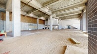 Located at 850 S Gadsden St in Tallahassee, Florida, this single-story commercial shell space presents a substantial, open floor plan ready for tenant build-out. The structure showcases an exposed concrete framework throughout, including visible columns, beams, and a flat ceiling deck that underscore the building's robust construction. Soaring ceiling heights in key areas of the space create a dramatic sense of volume, offering significant flexibility for a wide range of commercial uses.

Natural light is a defining feature, with large floor-to-ceiling windows and steel-framed glass storefronts spanning the perimeter walls. Dark brick masonry columns accent the window bays, lending an industrial-modern aesthetic to the façade. Multiple entry points, including double glass doors, provide convenient access and enhance the connection between the interior and exterior.

The open plan is organized around a concrete column grid, allowing for highly adaptable interior configurations. Infrastructure including overhead piping and conduit is already in place. A lower-level utility area with concrete slab and mechanical rough-ins is also present. The space is currently in active construction, offering prospective tenants the opportunity to customize the interior to their specific requirements from the ground up.