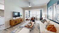Located at 3434 Laurens Rd in Greenville, South Carolina, this well-appointed single-floor residence combines contemporary design with comfortable living. The open-concept layout connects the living and sitting areas seamlessly, with wood-look flooring flowing throughout and ceiling fans providing both style and function. The living area is bright and inviting, featuring large windows dressed with decorative curtains that allow ample natural light.

The kitchen is thoughtfully designed with white shaker cabinetry, granite countertops, a classic subway tile backsplash, and a full suite of stainless steel appliances, including a range, microwave, and refrigerator. A convenient pantry with built-in hooks adds practical storage.

Multiple bedrooms offer comfortable retreats, each distinguished by stylish accent walls — including rich navy and soft teal hues — ceiling fans, and large windows with outdoor views. The rooms are generously sized and finished with the same wood-look flooring found throughout the home.

The bathrooms are finished with granite-topped white vanities, wood-look tile flooring, and shower-tub combinations accented with decorative curtains. A large mirror and modern lighting fixtures complete each bathroom's clean, polished look. Overall, the space presents a cohesive, modern aesthetic with thoughtful design details throughout.