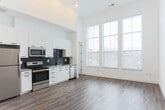 Located in Atlanta's Castleberry Hill neighborhood, this two-story space offers a thoughtfully designed interior with contemporary finishes throughout. The main level is anchored by a generous open living area with soaring ceilings and light wood-tone flooring that runs continuously through the space. Tall, multi-pane windows flood the interior with natural light and provide views of the surrounding neighborhood, enhancing the sense of volume and openness.

The kitchen is well-appointed with white shaker-style cabinetry extending to the ceiling, a dark navy subway tile backsplash, stone countertops, and a full suite of stainless steel appliances including a refrigerator, range, microwave, and dishwasher. A bathroom on the main level features wood-tone flooring, white subway tile in the shower, and clean, minimal fixtures.

A sculptural black spiral staircase serves as a design focal point, connecting the main level to the upper floor and continuing up to a private rooftop deck. The rooftop deck features natural wood plank decking, white parapet walls with integrated wall-mounted lighting, and open sky views of the Atlanta cityscape, making it an ideal outdoor extension of the living space.
