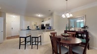 Located at 1644 Bass Rd in Macon, Georgia, this single-floor residence offers a thoughtfully designed layout with a seamless flow between living, dining, and kitchen spaces. The kitchen is equipped with stainless steel appliances, including a refrigerator, range, and microwave, complemented by white cabinetry, granite-style countertops, and warm hardwood-style flooring. A breakfast bar with seating connects the kitchen to the dining area, which features crown molding, a chandelier, and plush carpeting. The living room offers a relaxed ambiance with soft blue-green accent walls, crown molding, and abundant natural light. The primary bedroom includes a walk-in closet and an en-suite bathroom with a glass-enclosed shower and hardwood-style flooring. A second bedroom features soft blue accent walls, a ceiling fan, natural light from a glass door, and plush carpeting. An additional bedroom provides a bright, neutral-toned retreat with a bay-style window arrangement. The secondary bathroom is finished with white cabinetry, a large vanity mirror, and a shower/tub combination. Throughout the home, a consistent palette of warm neutrals and soft blue-green tones creates a cohesive and inviting atmosphere.