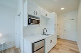 Located at 2445 San Pablo Ave in Berkeley, CA, Unit 2 is a thoughtfully designed studio that maximizes every square foot of its compact footprint. The space features a clean, modern aesthetic throughout, with warm light hardwood flooring, crisp white walls, and recessed lighting that create a bright and airy atmosphere.

The open-concept living and sleeping area is anchored by a large picture window that floods the room with natural light and offers pleasant views of surrounding greenery. A wall-mounted mini-split HVAC unit ensures year-round climate comfort. The bedroom area accommodates a full-sized bed and provides space for a desk, making it well-suited for both rest and work.

The kitchenette is efficiently outfitted with white shaker-style upper cabinets, a marble-look quartz countertop, a stainless steel sink with a matte black faucet, a built-in microwave, and a compact refrigerator — providing all essential cooking and storage needs in a streamlined layout.

A dedicated closet with a hanging rod offers practical storage, while the private bathroom features light hardwood-style flooring, clean white walls, and a modern toilet. The unit's overall design emphasizes simplicity, functionality, and a fresh, contemporary finish — ideal for those seeking an efficient and well-appointed living space in the heart of Berkeley.
