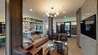Located in Stafford, TX, this single-floor clubhouse and amenity space showcases a sophisticated blend of industrial and contemporary design. Exposed brick walls, dark steel-framed floor-to-ceiling windows, and wood-look tile flooring establish a warm yet modern aesthetic throughout the space.

The main lounge area features a plush sofa, leather accent chairs, a glass coffee table, and a stylish sputnik-style chandelier overhead. A wall-mounted flat-screen television and textured accent wall add to the inviting atmosphere, making it an ideal gathering spot.

The kitchen and bar area is a standout feature, boasting sage-green cabinetry, a clean white quartz countertop island with bar seating, patterned encaustic floor tile, and large mirrored panels that visually expand the space. Built-in appliances and a utility sink make this area fully functional for entertaining.

Adjacent dining areas offer round wooden tables with upholstered chairs, surrounded by expansive black-framed windows that flood the space with natural light and provide views of the landscaped courtyard and pool area beyond.

A cozy reading nook with soft blue accent chairs and a sculptural pendant light sits beside a dramatic wall of steel-framed windows, offering serene outdoor views. Throughout the space, carefully curated artwork and décor reinforce the refined, welcoming character of this community amenity.
