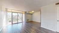 This single-floor space offers a thoughtfully designed layout that balances comfort and functionality. The living area is a standout feature, showcasing light-toned hardwood-style flooring that extends throughout the main spaces, complemented by large sliding glass doors that flood the room with natural light and provide direct access to an outdoor deck overlooking a green, landscaped setting.

Adjacent to the living area, the kitchen is well-equipped with rich dark cabinetry, granite countertops, a white subway tile backsplash, and a full suite of stainless steel appliances including a gas range, over-the-range microwave, and refrigerator. A double basin sink with a modern faucet adds to the kitchen's practicality.

The bedroom features warm, neutral carpeting and a window fitted with blinds, offering a quiet and comfortable retreat. The bathroom is cleanly finished with white subway tile surrounding a full soaking tub and shower combination, a wood-toned vanity with a modern rectangular sink, chrome fixtures, and a frosted window for natural light and privacy.

Throughout the space, neutral wall tones and clean lines create a cohesive, move-in-ready atmosphere that is both inviting and versatile.
