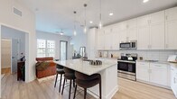 Located at 5701 Summerall Vista Circle in Riverview, FL, this well-appointed 2-bedroom, 2-bathroom residence offers a thoughtfully designed open-concept layout with modern finishes throughout. Light wood-style flooring flows seamlessly across the entire living space, creating a bright and cohesive aesthetic.

The kitchen is a standout feature, boasting crisp white shaker cabinetry extending to the ceiling, granite countertops, a subway tile backsplash, and stainless steel appliances including a range and microwave. A spacious island with seating for multiple guests serves as a natural gathering point, illuminated by stylish pendant lighting overhead.

The living room offers generous natural light through large windows framing views of palm trees, complemented by a ceiling fan for year-round comfort. Both bedrooms are well-proportioned and bright, each with access to walk-in closets fitted with wire shelving systems for organized storage.

The primary bathroom features a long granite vanity, white cabinetry, and a glass-enclosed shower with vertical tile surround. The second bathroom mirrors this refined aesthetic with a dual-sink granite vanity and a full soaking tub with tiled surround. Together, the two bathrooms deliver a clean, spa-inspired finish that ties the home's modern design together.