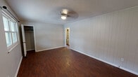 Located at 3300 Valley View Dr in Knoxville, Tennessee, this single-story home offers four bedrooms and one bathroom within a compact, efficiently arranged floor plan. Rich, dark hardwood-style flooring runs consistently throughout the home, lending warmth and visual continuity to each room.

The four bedrooms vary in size, with the primary bedroom being the most spacious. Bedrooms feature ceiling fans with light fixtures, neutral-toned walls with vertical paneling accents in select rooms, and closets — including a roomy walk-in closet in the primary bedroom and a bifold-door closet in another. One bedroom benefits from dual windows that bring in natural light and a view of the surrounding greenery.

The kitchen is well-equipped with white cabinetry extending to the ceiling for ample storage, dark laminate countertops, a double sink, and white appliances including an electric range and full-size refrigerator. Overhead cabinet shelving adds additional display or storage space.

The bathroom features white tile wainscoting, a wall-mounted sink, a medicine cabinet with a mirrored door, built-in shelving, and a vanity light. A hallway connects the main living areas, and a utility area with overhead cabinetry and an exterior door provides practical everyday access. The home presents a straightforward, functional layout suited for comfortable everyday living.