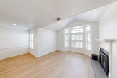 Located at 630 Smithfield Road in North Providence, Rhode Island, this one-bedroom unit offers a well-designed single-floor layout. The living room is an immediate highlight, featuring soaring vaulted ceilings, a striking bay window that invites generous natural light, and a classic fireplace with a white mantel — all complemented by light-toned hardwood-style flooring that flows throughout the main living areas.

The kitchen is thoughtfully designed with white cabinetry, gray countertops, and a peninsula that opens toward the living space, creating a connected, functional layout. Stainless steel appliances, including a microwave and dishwasher, accompany the electric range and refrigerator. A double-basin sink is neatly positioned at the corner of the countertop.

A hallway connects the living area to the bedroom and bathroom. The bedroom is generously proportioned, featuring plush wall-to-wall carpeting, a ceiling fan with lighting, a large window for natural light, and a wide double-door closet offering ample storage. The bathroom, visible in the dollhouse view, includes a full tub and vanity. Clean white walls and bright finishes throughout give the unit a fresh, move-in-ready appearance.