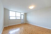 Located at 260 Wellesley St E in Toronto's Cabbagetown neighbourhood, this two-bedroom, one-bathroom unit offers a practical and well-appointed layout across a single floor. Classic parquet flooring runs throughout the living areas and bedrooms, lending warmth and a timeless character to the space. The entry foyer transitions smoothly between the tiled and wood-floored areas, creating a welcoming arrival point.

The kitchen is notably updated, featuring crisp white cabinetry with brushed nickel hardware, light stone-effect countertops, a white subway tile backsplash, and a stainless steel sink — all combining to create a clean, modern aesthetic.

The generously sized primary bedroom offers ample room and benefits from bright windows with urban views of the surrounding Toronto skyline. The second bedroom is also well-proportioned with its own window framing city views, making it suitable as a guest room, home office, or additional sleeping space.

The bathroom includes a full soaker tub and shower combination with tiled surround, complemented by marble-effect floor tiling. Clean white walls and crisp trim throughout the unit maintain a bright, neutral palette, making it a versatile and move-in ready space in the heart of Toronto.