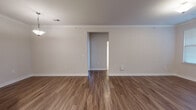 Located at 2110 Cinema Dr in Fuquay-Varina, NC, this single-floor residence offers a well-designed layout with a clean, modern aesthetic throughout. The open-concept living and dining area is anchored by rich wood-look flooring and crowned with elegant crown molding, creating a polished and inviting atmosphere. A peninsula kitchen seamlessly connects to the main living space and is outfitted with dark espresso cabinetry, granite countertops, a tile backsplash, and stainless steel appliances including a range, microwave, and refrigerator. Pendant lighting above the peninsula adds a contemporary touch, while a chandelier illuminates the adjacent dining area. The bedrooms are finished with plush carpeting and feature windows dressed with blinds that allow for ample natural light. The primary bathroom is a standout, boasting an L-shaped dual-sink vanity with dark cabinetry, white countertops, and large mirrors framed by wall-mounted lighting. A secondary bathroom provides a full tub-shower combination with tile flooring and a dark-cabinet vanity. Throughout the space, neutral wall tones, white trim, and consistent finishes create a cohesive and move-in-ready environment suited for comfortable everyday living.