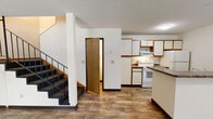 Located at 1811 16th St SE in Saint Cloud, Minnesota, this multi-floor home offers five bedrooms and two bathrooms spread across three well-proportioned floors. The main level features an open living room with wood-look flooring, natural light from multiple windows, a wall-mounted air conditioning unit, and a staircase with a classic metal railing leading to the upper levels. The kitchen is equipped with white cabinetry accented by wood trim, a white electric range, refrigerator, and a peninsula with dark countertops — ideal for both cooking and casual dining. The bathrooms feature tiled flooring and a full soaking tub. Bedrooms are found across all three floors and offer a mix of wood-look and carpeted flooring. Several bedrooms include built-in open shelving and closet units, providing generous storage space. A number of rooms feature baseboard heating and windows with blinds that bring in views of the surrounding greenery. Ceiling fans are present in select bedrooms for added comfort. Hallways connect the rooms across each floor, ensuring a practical and efficient flow throughout the home. Textured ceilings are consistent throughout, contributing to the home's classic residential character.