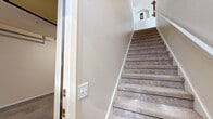 Located at 455 Ithaca Ct in Las Cruces, NM, this two-story, two-bedroom, two-bathroom home offers a well-organized layout across two levels. The garage level entry provides direct interior access, leading upstairs via carpeted stairs with arched architectural detailing along the stairwell. The main living level hosts an open-concept space combining the living room, dining area, and kitchen. The living room features light wood-look flooring, a ceiling fan, large windows that invite natural light, and rustic floating wood shelves. The dining area includes light wood flooring, a pendant light fixture, and access to an arched hallway. The kitchen offers a breakfast bar, warm wood cabinetry, tile flooring, and a pantry closet for added storage. A dedicated laundry room with side-by-side washer and dryer is conveniently located on the main level. Both bathrooms feature tile flooring, vanities with wood cabinetry, and tub-shower combinations. The two bedrooms are carpeted and filled with natural light from multiple windows, with the generously sized primary bedroom offering ample square footage and closet space. Throughout the home, neutral tones and Southwestern design accents create a warm and cohesive atmosphere.