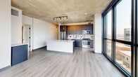 This contemporary 850 square foot apartment in Chicago offers a blend of urban sophistication and practical living. The space features two bedrooms, including a primary bedroom of 180 square feet, and two bathrooms. Floor-to-ceiling windows dominate the living areas, flooding the space with natural light and providing stunning views of the Chicago cityscape. The apartment's industrial-chic aesthetic is emphasized by exposed concrete ceilings, creating a loft-like atmosphere.

The open-concept layout seamlessly integrates the living, dining, and kitchen areas. The kitchen boasts modern appliances, dark wood cabinetry, and a contrasting white island, perfect for casual dining or entertaining. Light wood-look flooring throughout the main living areas adds warmth to the space.

Both bathrooms are outfitted with modern fixtures, including illuminated mirrors and sleek vanities. The bedrooms feature plush carpeting and ample closet space with floor-to-ceiling built-ins. Throughout the apartment, the neutral color palette creates a canvas for personalization.

The property's single floor layout and thoughtful design maximize the use of space, making it an ideal urban dwelling for those seeking a balance of style and functionality in the heart of Chicago.