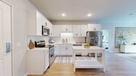 This thoughtfully designed 2-bedroom, 2-bathroom residence in Waconia, MN offers a clean, modern aesthetic with warm, inviting touches throughout its single-floor layout. The kitchen is a standout space, featuring crisp white shaker cabinets with matte black hardware, a classic subway tile backsplash, white quartz countertops, and a full suite of stainless steel appliances. Light wood-look flooring runs seamlessly through the kitchen and living areas, enhancing the bright, airy feel. The living room is generously proportioned, with a sliding glass door opening to a private balcony that brings in natural light and outdoor views. The two bedrooms are well-appointed, each with plush carpeting and dedicated closet space. The primary bedroom offers a comfortable, serene retreat, while the second bedroom is equally versatile. Both bathrooms are finished with white vanity cabinetry, quartz countertops, and matching matte black hardware. One bathroom includes a tiled tub-shower combination, while the other features a walk-in shower-ready layout. A hallway connects the private quarters with efficient flow. Recessed lighting and neutral wall tones complete the polished, move-in-ready interior of this well-appointed Waconia residence.