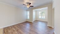Located at 450 Seasons Place Northwest in Concord, NC, this well-appointed 2-bedroom, 2-bathroom single-floor home offers a thoughtfully designed layout with quality finishes throughout. The open living and dining area is anchored by rich hardwood-style flooring, crown molding, and a ceiling fan with light fixture, while multiple windows dressed with blinds fill the space with generous natural light. An adjacent dining area features its own pendant light and additional windows, creating a bright, welcoming atmosphere. The kitchen is equipped with warm cherry wood cabinetry, granite countertops, black appliances including a refrigerator, range, and microwave, and a peninsula with bar seating that connects seamlessly to the dining space. Tile flooring and a chandelier complete the kitchen's functional and stylish design. Both bedrooms continue the hardwood-style flooring and offer ample natural light through blinded windows, with crown molding adding an elegant touch. The primary bedroom includes access to a spacious walk-in closet outfitted with wire shelving. The bathrooms feature granite-topped vanities with cherry cabinetry and tile flooring. A dedicated laundry area with built-in shelving adds everyday convenience to this well-rounded home.